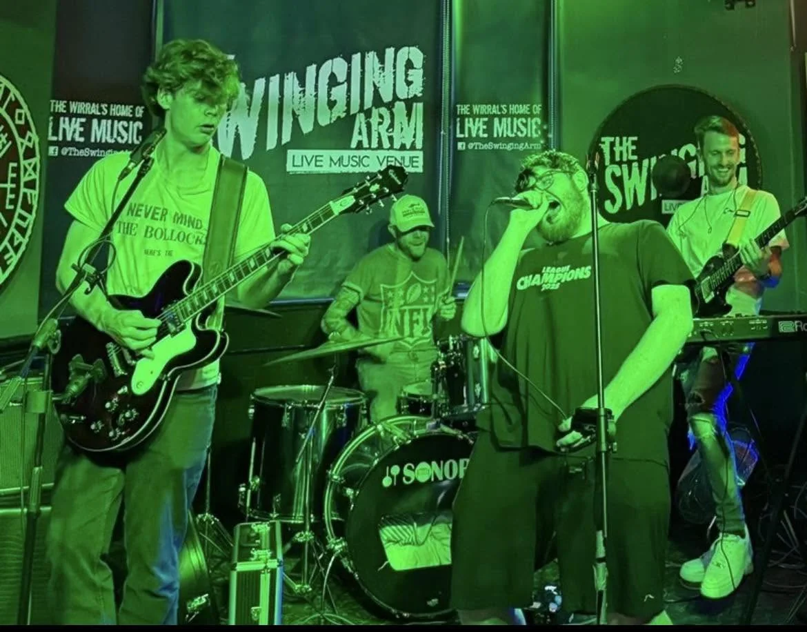 Last Laugh Lane under green stage lights, performing at The Swinging Arm on the Wirral